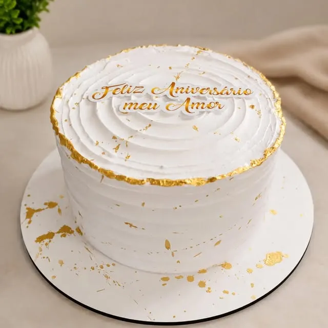 Bolo branco com detalhes dourados e frase de aniversário